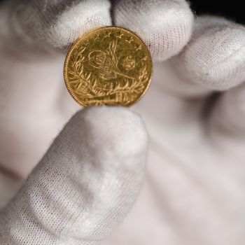 A gloved hand holding a gold coin