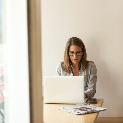 A woman buying coins online from her laptop in a corner A woman buying coins online from her laptop in a corner